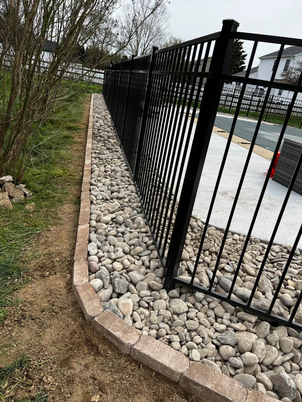 Black aluminum pool fence with river rock border