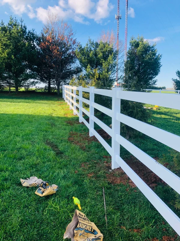 Vinyl ranch rail fence along evergreen row