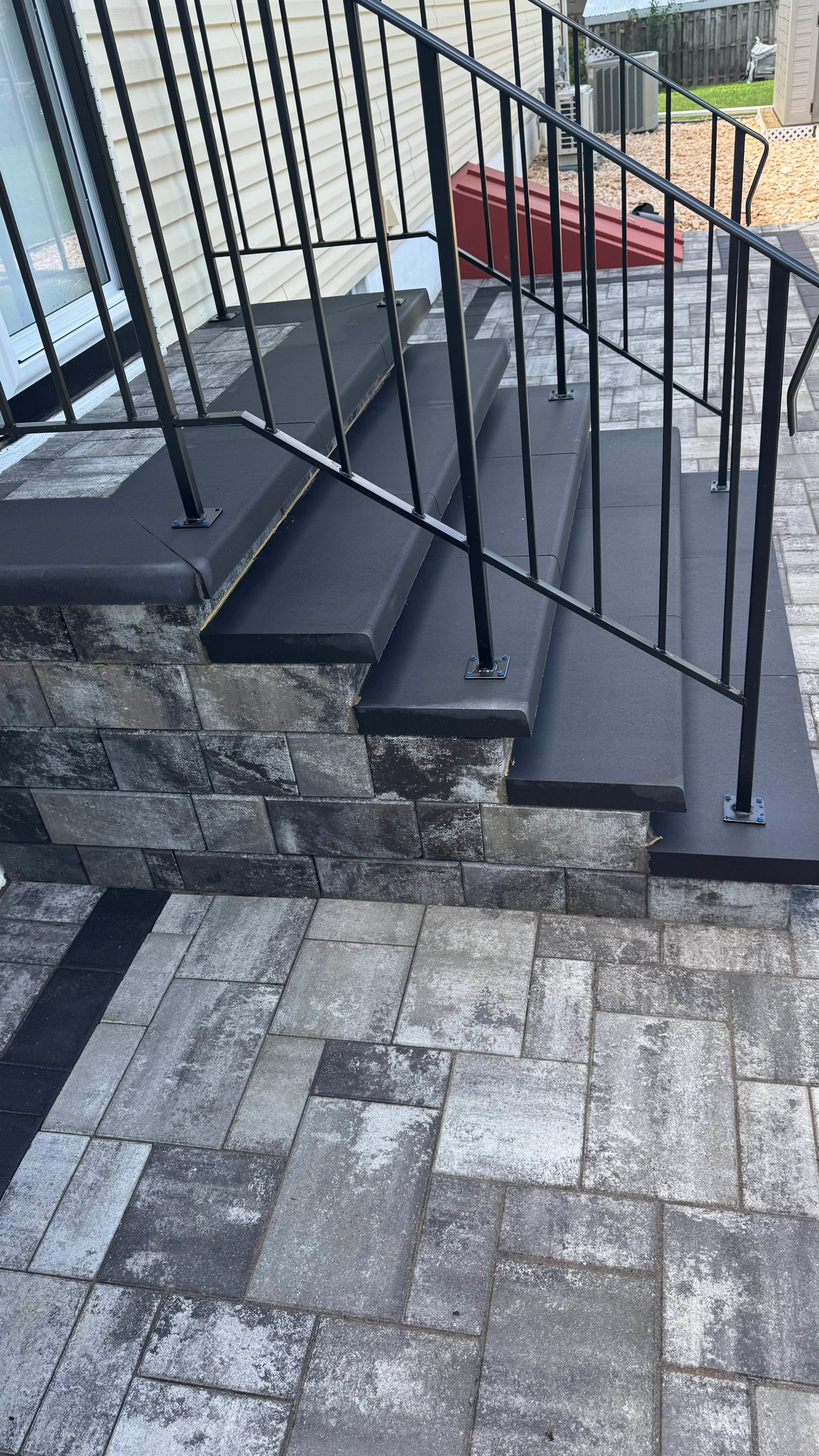 A multi-level paver patio with integrated paver steps leading to a house.